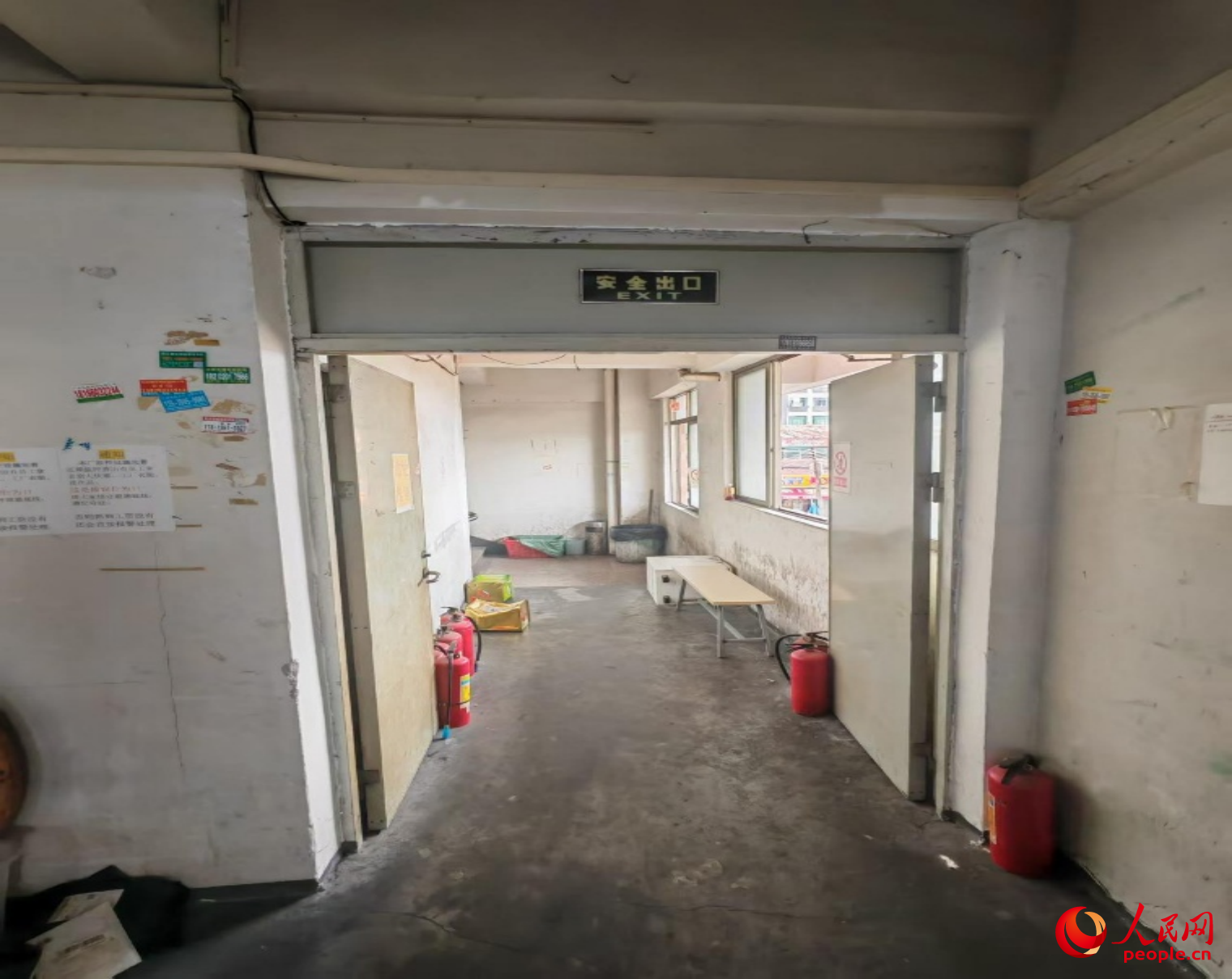 被灭火器抵住敞开的常闭式防火门,门口还扔有两个装过强力清洁剂和衣车油的空桶,疏散通道还堆有其它杂物。人民网记者 王子锋摄